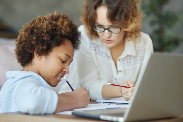 A woman and a young girl collaborating on a laptop, engrossed in their work.