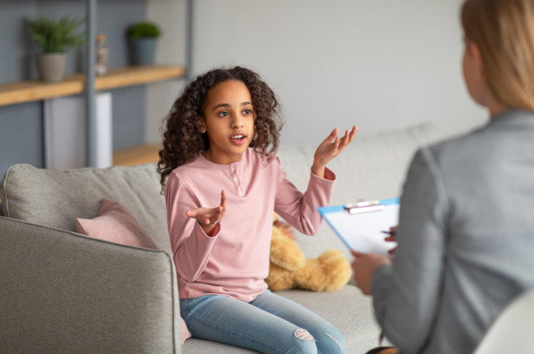 A girl and her mother sitting on a couch, enjoying each other's company in a cozy setting.